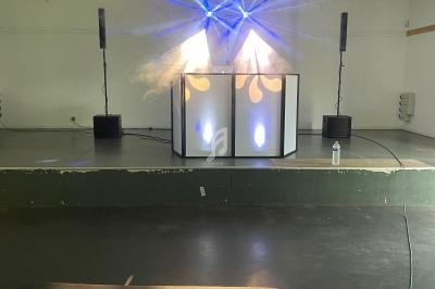 Installation de matériel de sonorisation et d'éclairage avec un vidéoprojecteur au premier plan dans une salle.