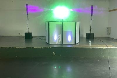 Installation de matériel de sonorisation et d'éclairage avec effets lumineux verts dans une salle vide.