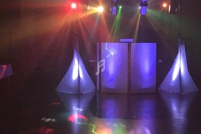 Jeu de lumières colorées projetées dans une salle sombre avec un équipement de sonorisation en arrière-plan.