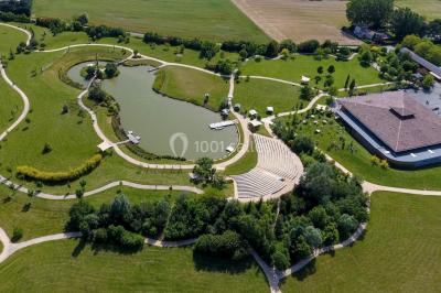 Un artiste sur échasses interagit avec une femme dans un espace intérieur éclairé, avec des spectateurs en arrière-plan.