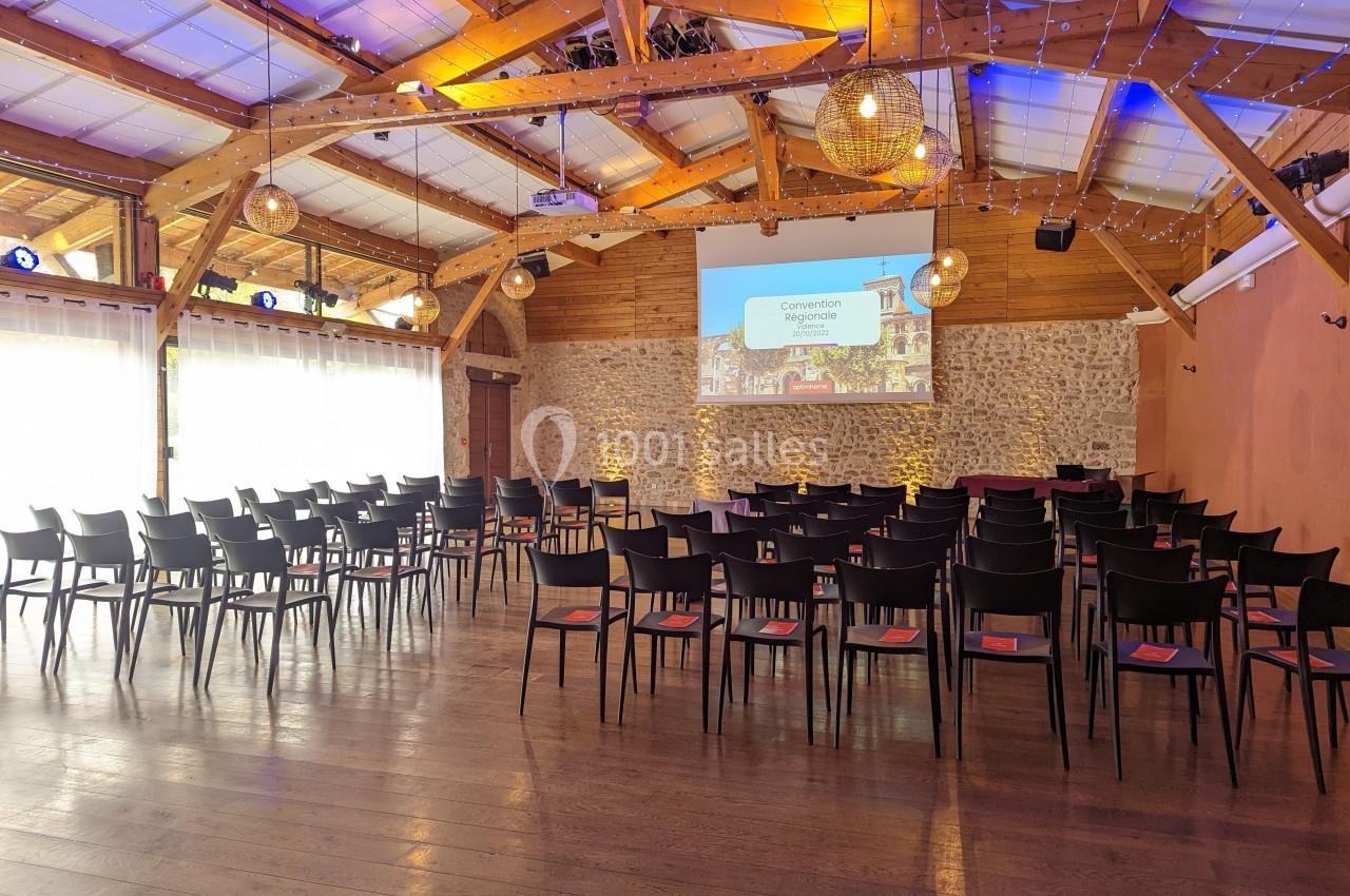Salle de conférence avec chaises alignées, écran de projection allumé et décoration lumineuse au plafond.
