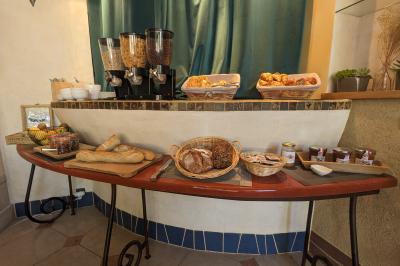 Un artiste sur échasses interagit avec une femme dans un espace intérieur éclairé, avec des spectateurs en arrière-plan.