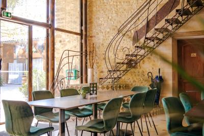 Un artiste sur échasses interagit avec une femme dans un espace intérieur éclairé, avec des spectateurs en arrière-plan.