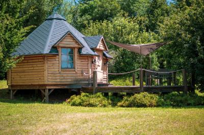 Un artiste sur échasses interagit avec une femme dans un espace intérieur éclairé, avec des spectateurs en arrière-plan.