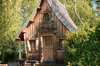 Un artiste sur échasses interagit avec une femme dans un espace intérieur éclairé, avec des spectateurs en arrière-plan.