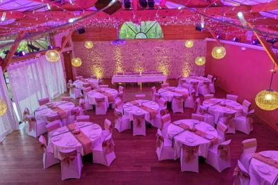 Un artiste sur échasses interagit avec une femme dans un espace intérieur éclairé, avec des spectateurs en arrière-plan.