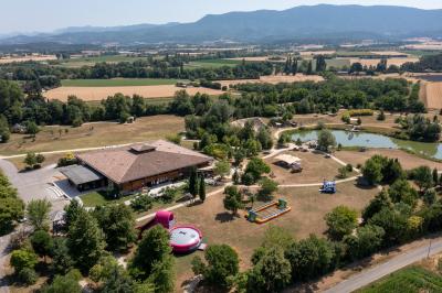Un artiste sur échasses interagit avec une femme dans un espace intérieur éclairé, avec des spectateurs en arrière-plan.