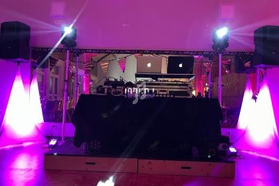 Installation de matériel DJ avec lumières violettes et projecteurs dans une salle décorée pour un événement.