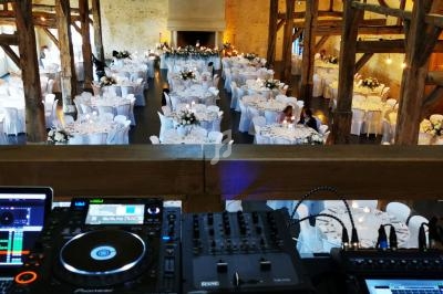 Salle de réception décorée pour un événement, vue depuis une mezzanine avec une table de mixage au premier plan.