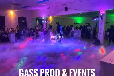 Un couple danse au centre d'une salle éclairée par des lumières colorées, entouré de fumée et d'invités assis.