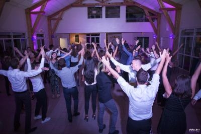 Personnes dansant ensemble dans une salle éclairée par des lumières violettes, ambiance festive et conviviale.
