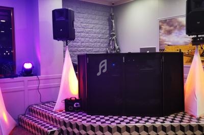 Installation de matériel de sonorisation et éclairage coloré dans une salle avec une estrade et des décorations murales.