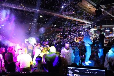 Groupe de personnes dans une discothèque animée, éclairée par des lumières colorées et entourée de bulles.