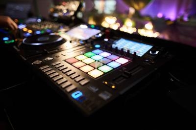 Table de mixage avec des boutons lumineux colorés et des commandes, utilisée dans un environnement faiblement éclairé.