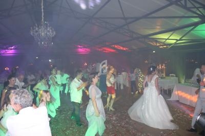 Des invités dansent sur une piste éclairée de lumières colorées lors d'une réception festive en intérieur.