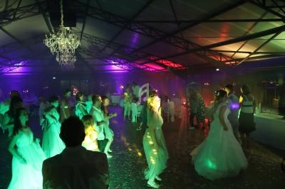 Des invités dansent sous des lumières colorées dans une salle de réception avec un lustre suspendu.