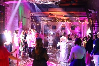 Des invités dansent et discutent dans une salle décorée de guirlandes lumineuses lors d'une réception festive.