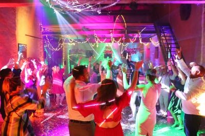 Groupe de personnes dansant sous des lumières colorées dans une salle décorée pour une fête.