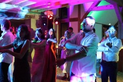 Des personnes dansent en groupe sous des lumières colorées dans une ambiance festive en intérieur.