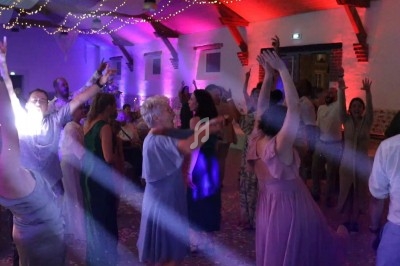 Personnes dansant sous des lumières colorées dans une salle festive avec une ambiance animée.