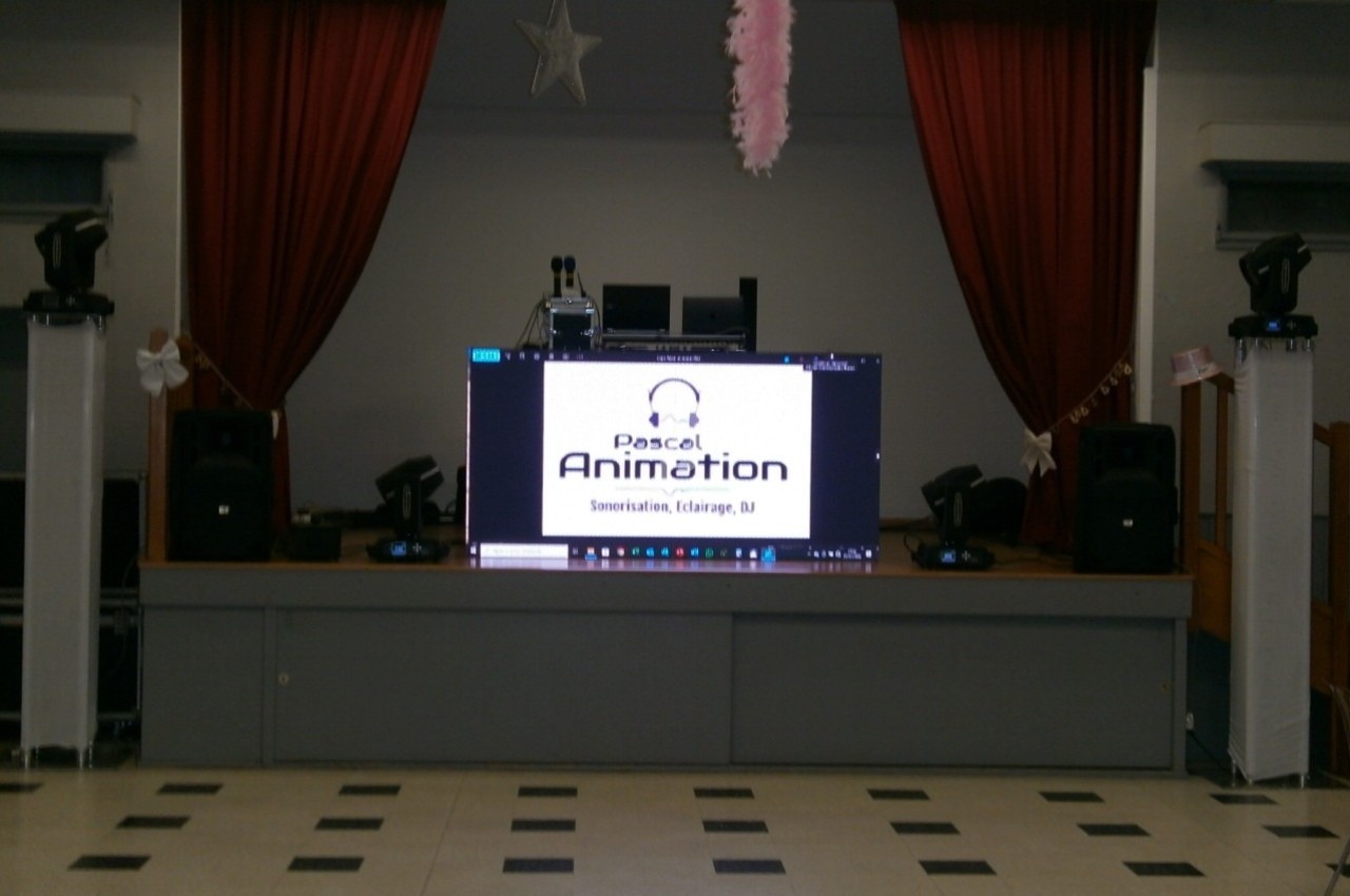 Scène avec écran affichant ’Pascal Animation’, entouré de rideaux rouges, haut-parleurs et éclairages.