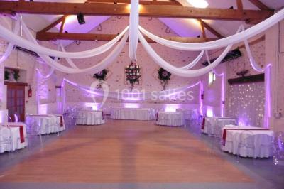 Terrain de sport en plein air avec pelouse et piste en terre, entouré de maisons et d'arbres sous un ciel dégagé.