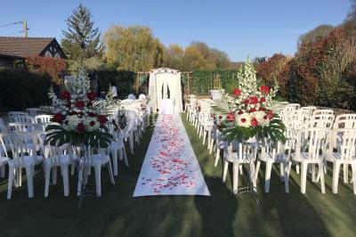 Terrain de sport en plein air avec pelouse et piste en terre, entouré de maisons et d'arbres sous un ciel dégagé.