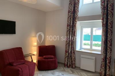 Terrain de sport en plein air avec pelouse et piste en terre, entouré de maisons et d'arbres sous un ciel dégagé.