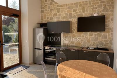 Terrain de sport en plein air avec pelouse et piste en terre, entouré de maisons et d'arbres sous un ciel dégagé.