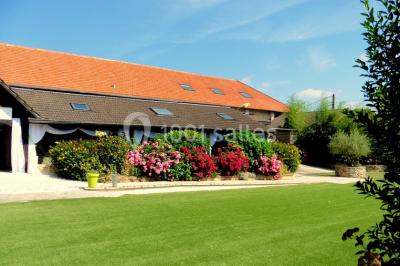 Terrain de sport en plein air avec pelouse et piste en terre, entouré de maisons et d'arbres sous un ciel dégagé.