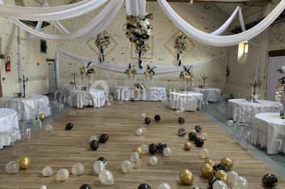 Terrain de sport en plein air avec pelouse et piste en terre, entouré de maisons et d'arbres sous un ciel dégagé.