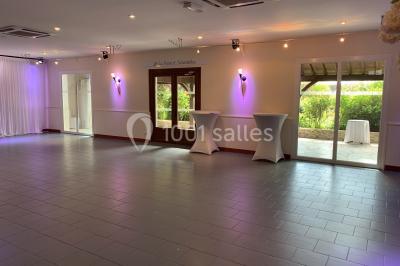 Terrain de sport en plein air avec pelouse et piste en terre, entouré de maisons et d'arbres sous un ciel dégagé.