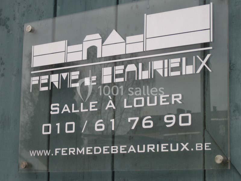 Location salle Court-Saint-Étienne (Brabant wallon) - Ferme de Beaurieux #6 Panneau en plexiglas indiquant ’Ferme de Beaurieux’, avec contact pour location de salle et site web.