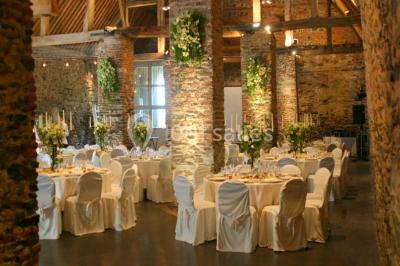 Miniature Location salle Court-Saint-Étienne (Brabant wallon) - Ferme de Beaurieux #1 Charpente en bois apparente d'un bâtiment ancien avec des murs en briques et un éclairage intérieur chaleureux.