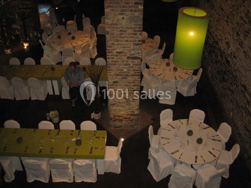 Location salle Court-Saint-Étienne (Brabant wallon) - Ferme de Beaurieux #12 Salle de réception avec des tables rondes et rectangulaires dressées, chaises blanches et grandes lampes vertes.