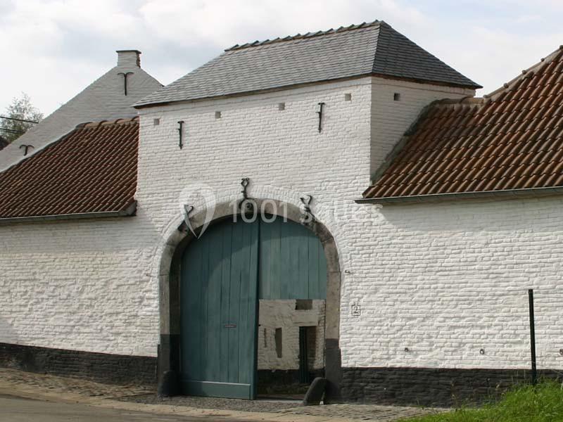 Location salle Court-Saint-Étienne (Brabant wallon) - Ferme de Beaurieux #13 Porte cochère en bois bleu encadrée par des murs en briques blanches et un toit en tuiles rouges.