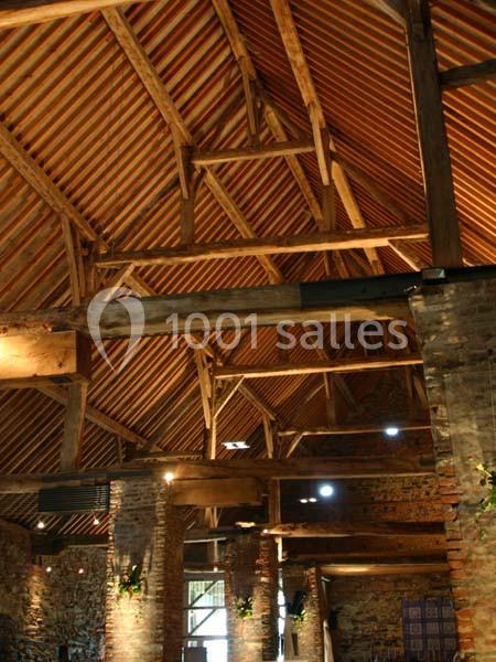 Location salle Court-Saint-Étienne (Brabant wallon) - Ferme de Beaurieux #20 Charpente en bois apparente d'un bâtiment ancien avec des murs en briques et un éclairage intérieur chaleureux.