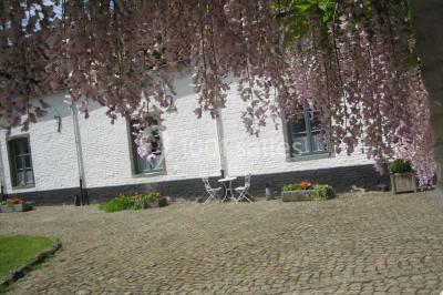 Paysage hivernal avec arbres dénudés, sol enneigé, clôture en bois et maisons en arrière-plan sous un ciel gris.