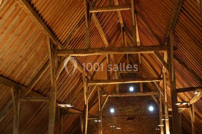 Paysage hivernal avec arbres dénudés, sol enneigé, clôture en bois et maisons en arrière-plan sous un ciel gris.