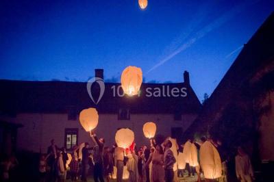 Paysage hivernal avec arbres dénudés, sol enneigé, clôture en bois et maisons en arrière-plan sous un ciel gris.