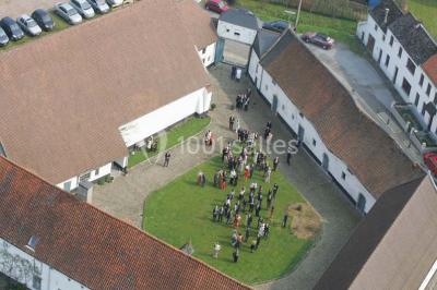 Paysage hivernal avec arbres dénudés, sol enneigé, clôture en bois et maisons en arrière-plan sous un ciel gris.