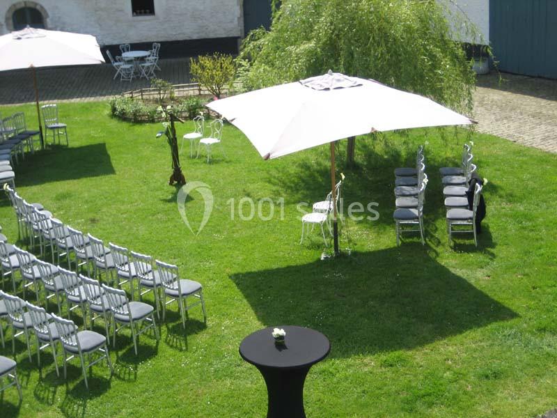 Chaises disposées en extérieur sur une pelouse avec des parasols blancs, préparées pour un événement en plein air.