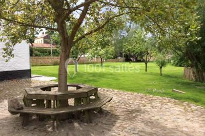 Paysage hivernal avec arbres dénudés, sol enneigé, clôture en bois et maisons en arrière-plan sous un ciel gris.