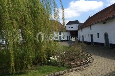 Paysage hivernal avec arbres dénudés, sol enneigé, clôture en bois et maisons en arrière-plan sous un ciel gris.