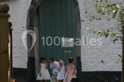 Paysage hivernal avec arbres dénudés, sol enneigé, clôture en bois et maisons en arrière-plan sous un ciel gris.