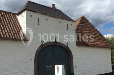 Paysage hivernal avec arbres dénudés, sol enneigé, clôture en bois et maisons en arrière-plan sous un ciel gris.