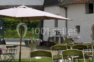 Paysage hivernal avec arbres dénudés, sol enneigé, clôture en bois et maisons en arrière-plan sous un ciel gris.