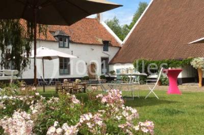 Paysage hivernal avec arbres dénudés, sol enneigé, clôture en bois et maisons en arrière-plan sous un ciel gris.
