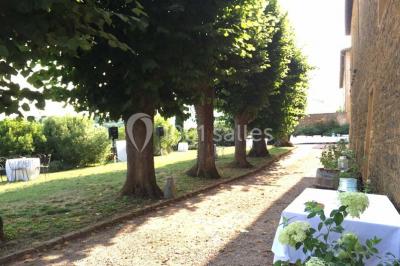 Bouteille de vin rouge posée sur une surface en pierre, avec des fleurs floues et un paysage en arrière-plan.