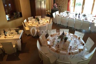 Bouteille de vin rouge posée sur une surface en pierre, avec des fleurs floues et un paysage en arrière-plan.